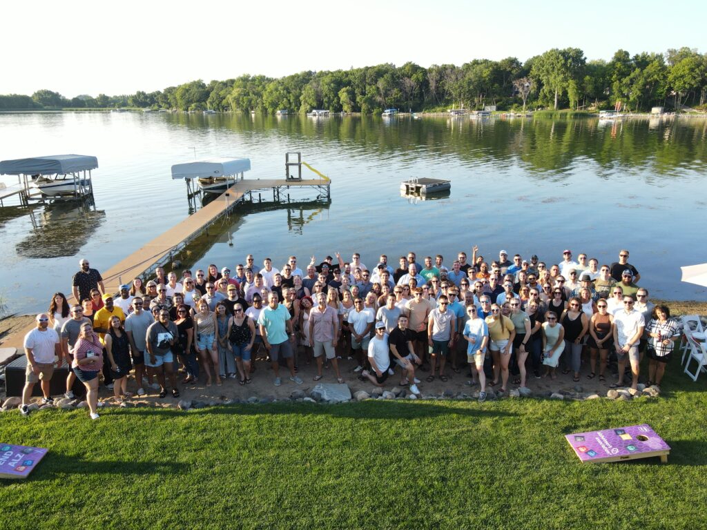Team photo of all employees at owner's house in front of lake